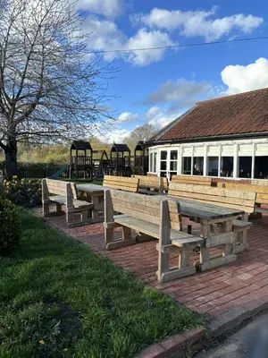 a group of wooden benches in front of a building at The Half Moon Inn Rushall IP21 4QD in Pulham Saint Mary the Virgin