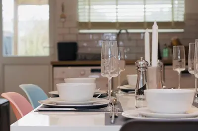a table with plates and wine glasses on it at Gulliver's Cottage in Frinton-On-Sea in Frinton-on-Sea