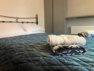 a bed with a blanket and two towels on it at Gulliver's Cottage in Frinton-On-Sea in Frinton-on-Sea