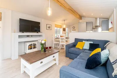 a living room with a blue couch and a fireplace at Beach Lodge - Aldeburgh Coastal Cottages in Sizewell