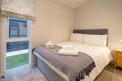 a bedroom with a bed and a window at Beach Lodge - Aldeburgh Coastal Cottages in Sizewell