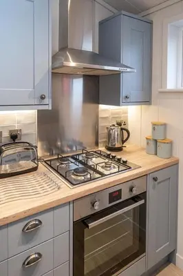 a kitchen with a stove top oven and blue cabinets at Beach Lodge - Aldeburgh Coastal Cottages in Sizewell