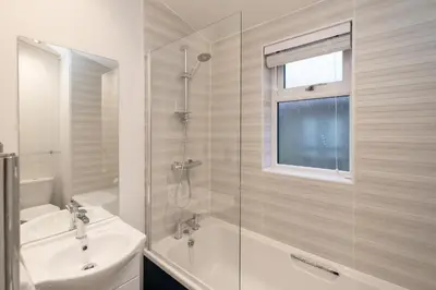 a white bathroom with a shower and a sink at Beach Lodge - Aldeburgh Coastal Cottages in Sizewell