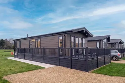 a small house with a black fence around it at Beach Lodge - Aldeburgh Coastal Cottages in Sizewell