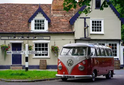 an old red and white bus parked in front of a building at The Peacock Inn in Chelsworth