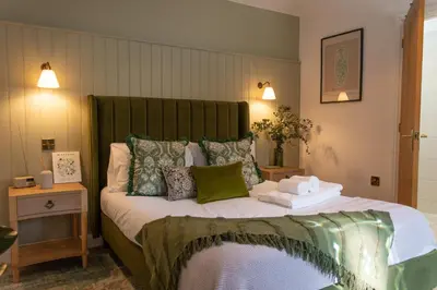 a bedroom with a large bed with a green headboard at The Peacock Inn in Chelsworth