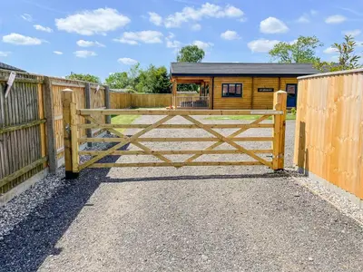 a wooden gate in front of a fence with a house at Aylesbury Lodge in Halstead