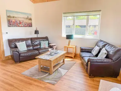 a living room with leather couches and a coffee table at Aylesbury Lodge in Halstead