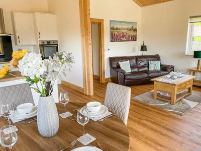 a living room with a table with a vase of flowers at Aylesbury Lodge in Halstead