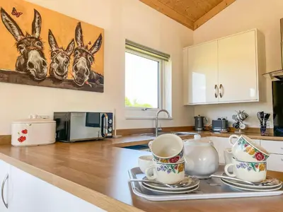 a kitchen with cups and saucers on a counter at Aylesbury Lodge in Halstead