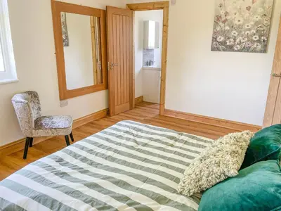 a bedroom with a bed and a chair and a mirror at Aylesbury Lodge in Halstead