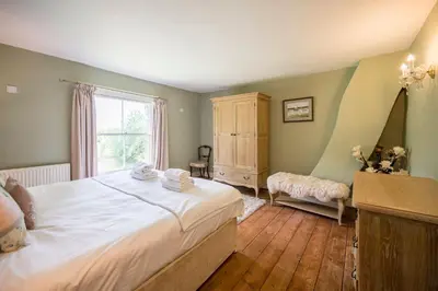 a bedroom with a large bed and a window at The Farmhouse Boundary Farm Framlingham in Woodbridge