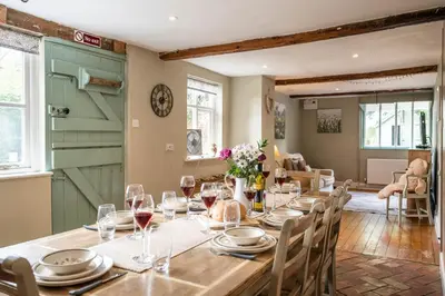 a dining room with a long table with wine glasses at The Farmhouse Boundary Farm Framlingham in Woodbridge