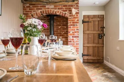 a table with glasses of wine and a brick wall at The Farmhouse Boundary Farm Framlingham in Woodbridge