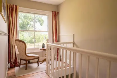 a white staircase with a chair and a window at The Farmhouse Boundary Farm Framlingham in Woodbridge