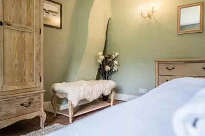 a bedroom with a bed and a dresser and flowers at The Farmhouse Boundary Farm Framlingham in Woodbridge