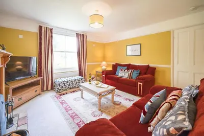 a living room with a red couch and a tv at The Farmhouse Boundary Farm Framlingham in Woodbridge