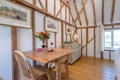 a dining room with a wooden table and chairs at The Hayloft Boundary Farm, Framlingham in Woodbridge