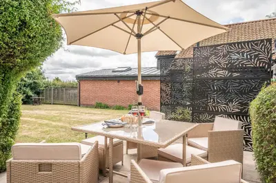 a table and chairs with an umbrella on a patio at The Hayloft Boundary Farm, Framlingham in Woodbridge