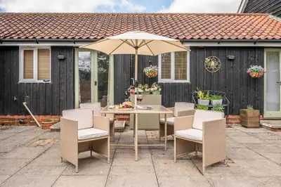 a table and chairs with an umbrella on a patio at The Cartlodge Boundary Farm, Framlingham in Woodbridge
