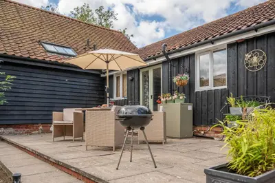 a bbq grill on a patio next to a house at The Cartlodge Boundary Farm, Framlingham in Woodbridge