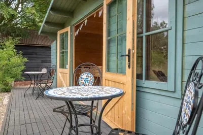 a patio with a table and chairs on a house at Sage Shepherds Hut Boundary Farm, Framlingham in Woodbridge