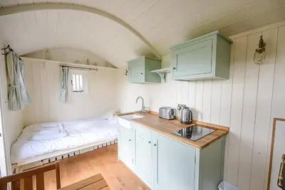 a kitchen with a bed and a sink in a room at Sage Shepherds Hut Boundary Farm, Framlingham in Woodbridge