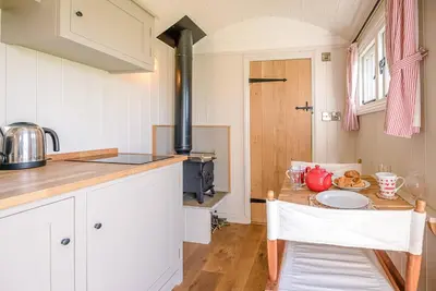 a kitchen with a table and a stove top oven at Thyme Shepherds Hut Boundary Farm, Framlingham in Woodbridge