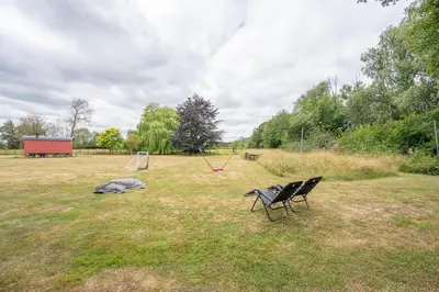 two chairs sitting in a field with a playground at Thyme Shepherds Hut Boundary Farm, Framlingham in Woodbridge
