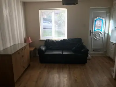 a living room with a black leather couch and a door at Comfortable Billericay Home in Billericay
