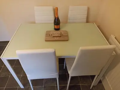a bottle of champagne sitting on a table with two white chairs at Comfortable Billericay Home in Billericay