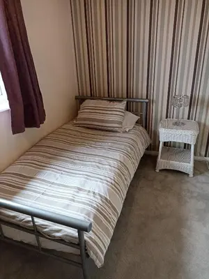 a bed sitting in a room with a window at Comfortable Billericay Home in Billericay