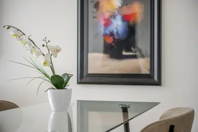 a vase with flowers on a table next to a painting at Luxury Parkway Apartment in Chelmsford City in Chelmsford