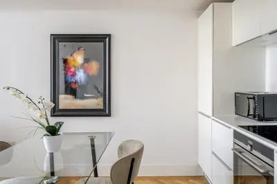 a white kitchen with a glass table and a microwave at Luxury Parkway Apartment in Chelmsford City in Chelmsford