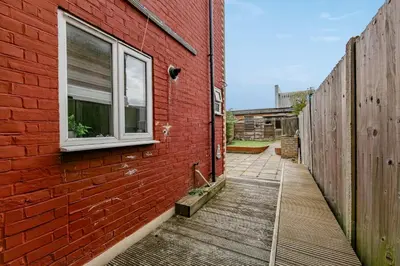 a red brick building with a window and a wooden walkway at The White Rose Crown, Free Parking & Wifi, 10beds in Colchester