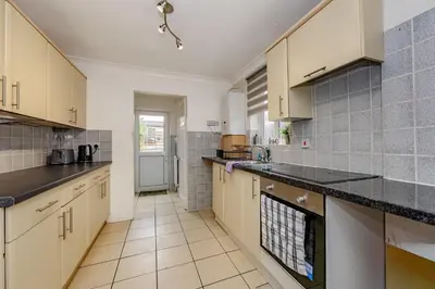 a kitchen with tan cabinets and black counter tops at The White Rose Crown, Free Parking & Wifi, 10beds in Colchester