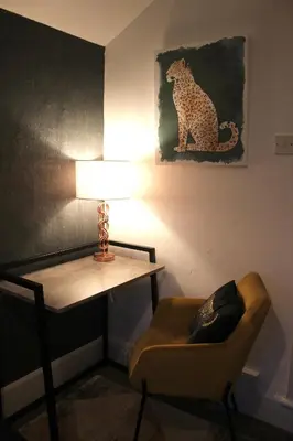 a room with a desk and a chair and a lamp at The Velveteen Townhouse in Colchester