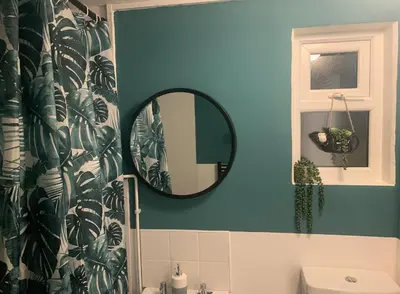 a bathroom with a mirror and a blue wall at The Velveteen Townhouse in Colchester