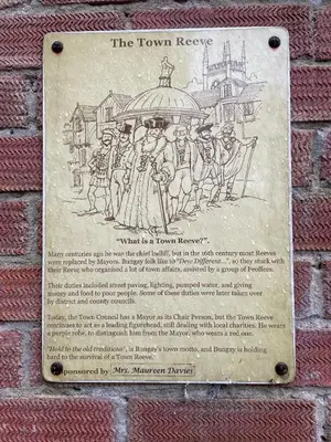 a plaque on a brick wall with a drawing of a group of people at Loft in Bungay in Bungay