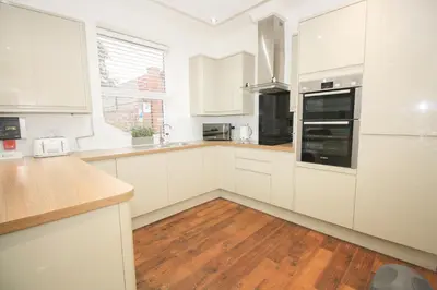a kitchen with white cabinets and a wooden floor at Roman Quarter in Colchester
