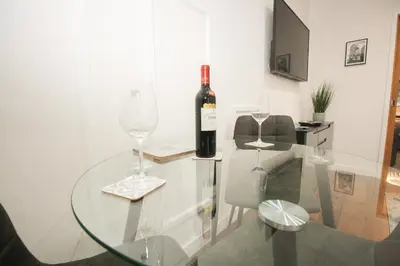 a glass table with a bottle of wine and two glasses at Roman Quarter in Colchester