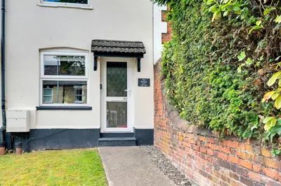 a white house with a brick wall and a door at The Retreat on Risbygate in Bury Saint Edmunds