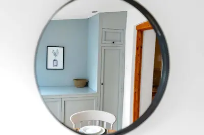a mirror reflecting a room with a table and a chair at The Retreat on Risbygate in Bury Saint Edmunds