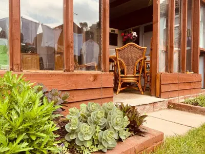 a porch of a house with a chair and some plants at Hikers & Bikers Refuge in Ipswich