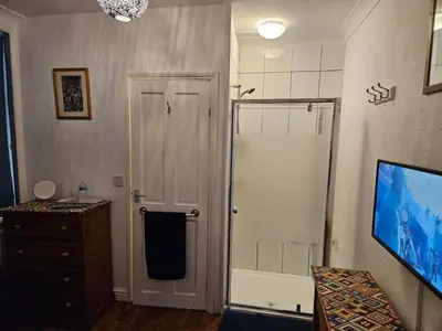 a bathroom with a shower stall and a television at Hikers & Bikers Refuge in Ipswich