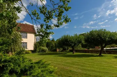 a large grassy yard with a house and trees at Pounce Hall -Stunning historic home in rural Essex in Saffron Walden