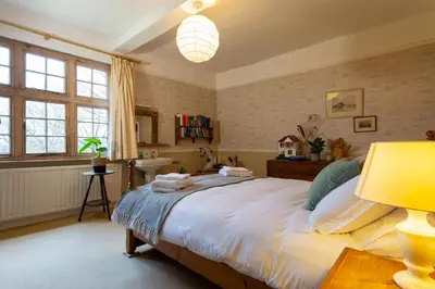a bedroom with a large bed and a lamp at Pounce Hall -Stunning historic home in rural Essex in Saffron Walden
