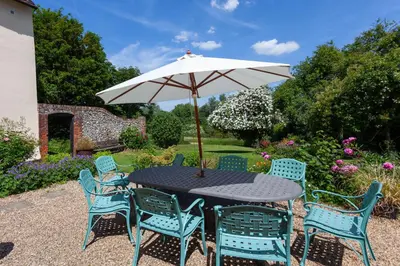 a table and chairs with an umbrella in a garden at Pounce Hall -Stunning historic home in rural Essex in Saffron Walden