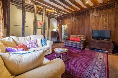 a living room with a couch and a tv at Extraordinary 15th Century timber framed cottage in famous Medieval village - The Tryst in Lavenham