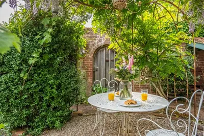 a white table with two glasses of orange juice at Extraordinary 15th Century timber framed cottage in famous Medieval village - The Tryst in Lavenham